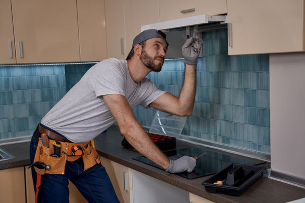 An appliance technician installing a range hood 