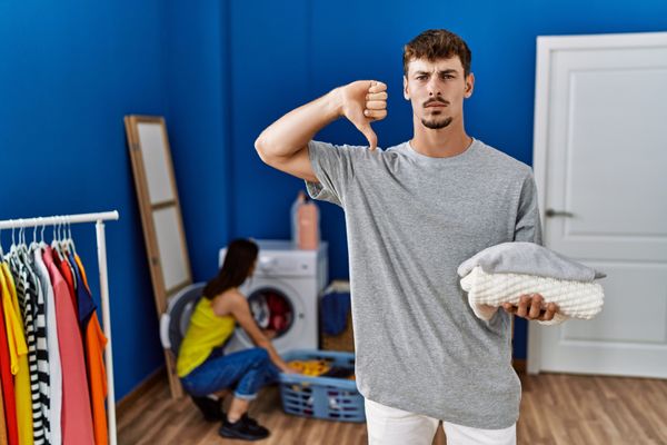 A man holding laundry giving a thumbs down 