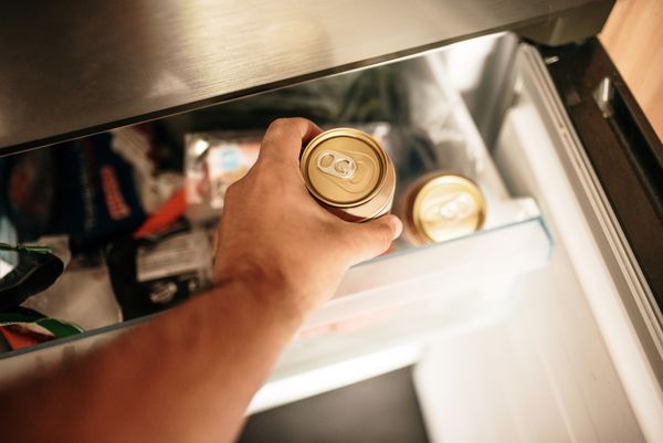 A man grabbing a can from a fridge