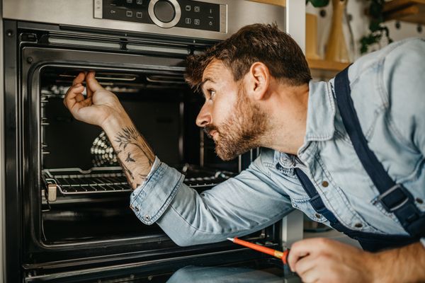 An appliance technician installing a wall oven 