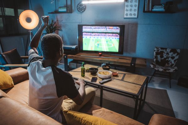 A back POV of a man on a couch watching soccer