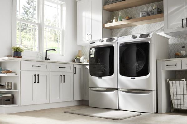 A Maytag MHW5630HW front load washer and dryer pair in a laundry room 