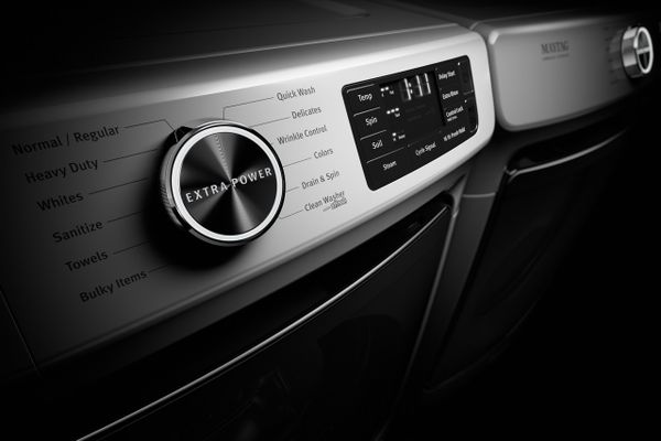 A close-up of the Maytag MHW6630HW front load washer against a black background 