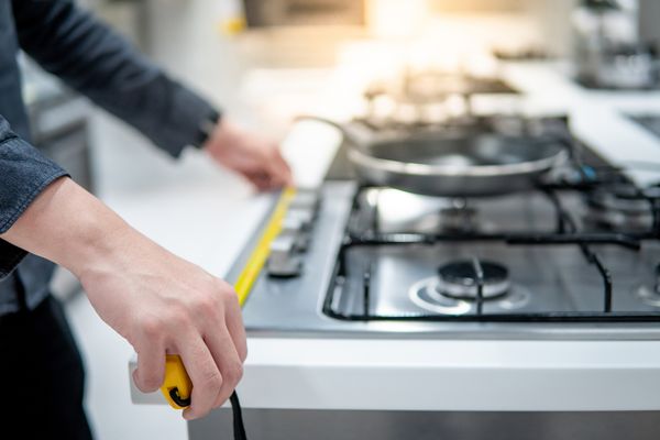 A person measuring a gas cooktop 