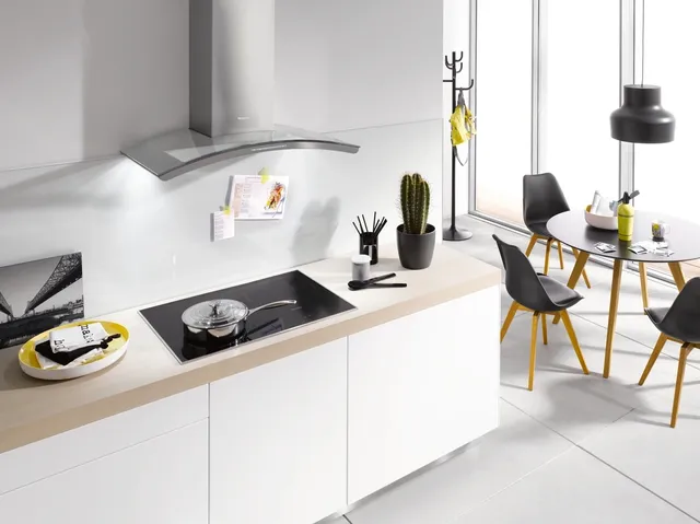 front view of a modern white kitchen with an induction cooktop and range hood