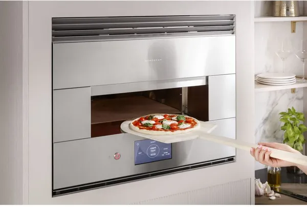 A person inserting a pizza into the Monogram ZEP30FRSS hearth oven 