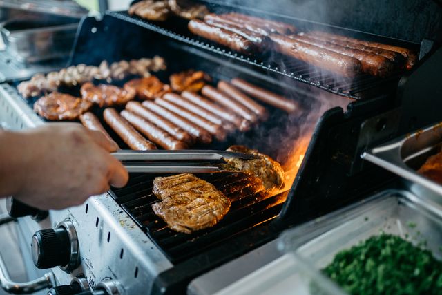 View of various meats being grilled on gas grill