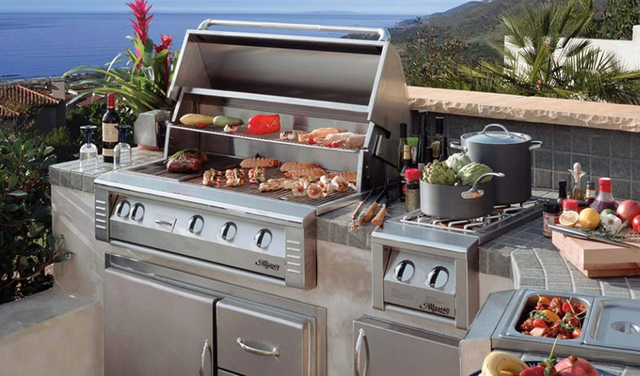 Front view of an Alfresco grill and outdoor kitchen on a backyard patio next to the ocean