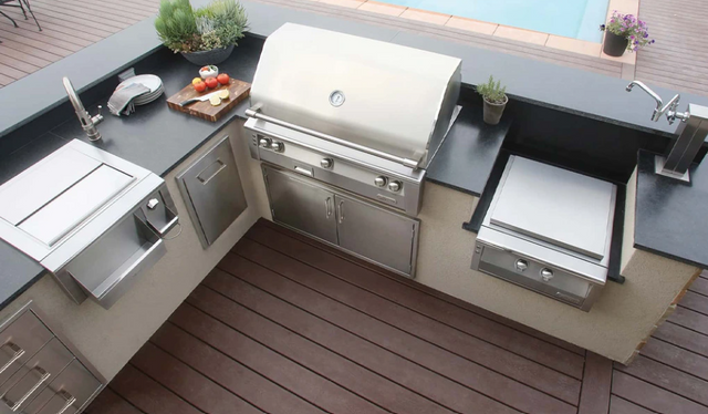 Top view of a modern outdoor kitchen area with an Alfresco built in grill all next to a pool.