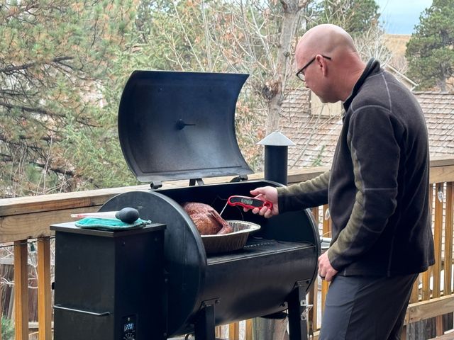 View of a man smoking a turkey in a pellet grill