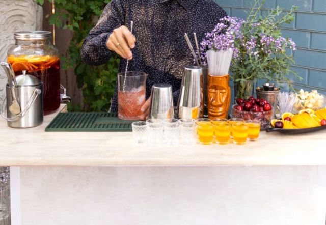 Front view of a person making drinks at a small outdoor bar.