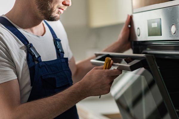 An appliance technician looking into an oven 