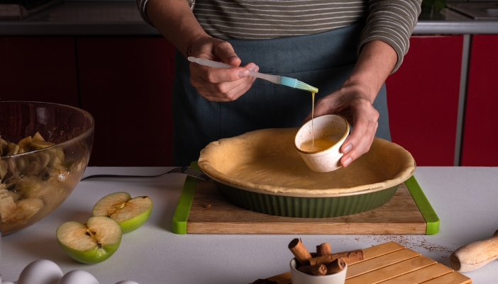 Woman coating pie crust in egg