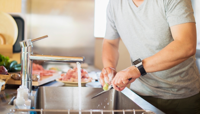 Closeup of someone hand washing a knife in the sink