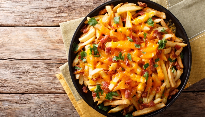 Closeup of a dish of cheese fries with bacon