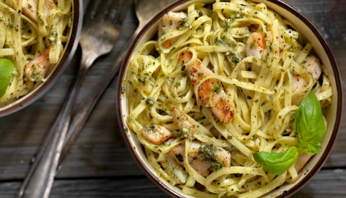 Two bowls of a petso pasta sit son a gray table.