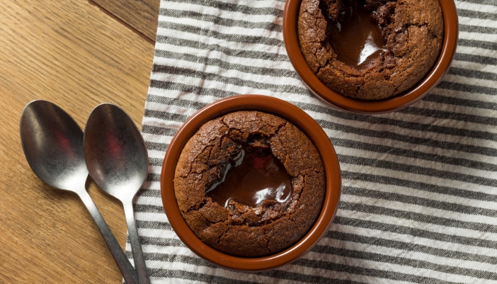 Two chocolate molton lava cakes on a black and white striped cloth.