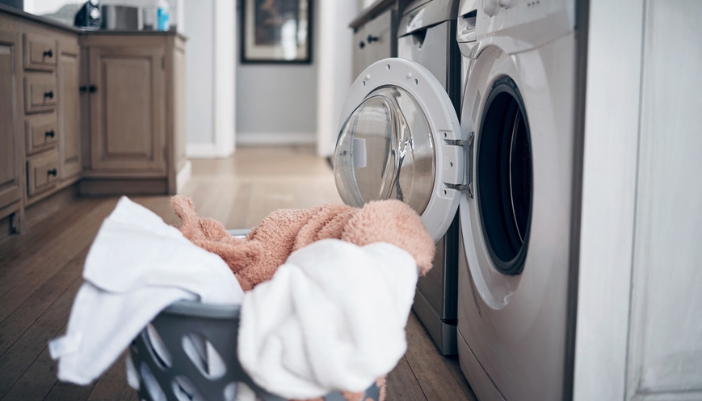  A laundry basket filled with blankets sits outside an open dryer.