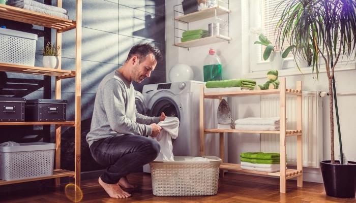 Man loading machine in laundry space with lots of shelves