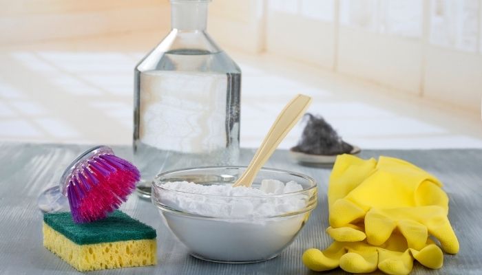bowl of baking soda next to sponge and gloves