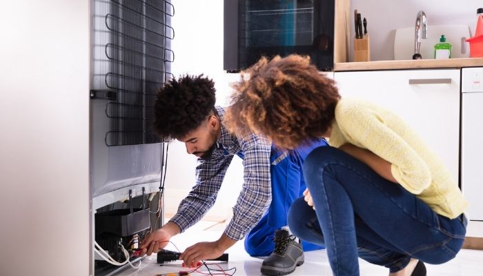 repairmann looking over fridge with customer