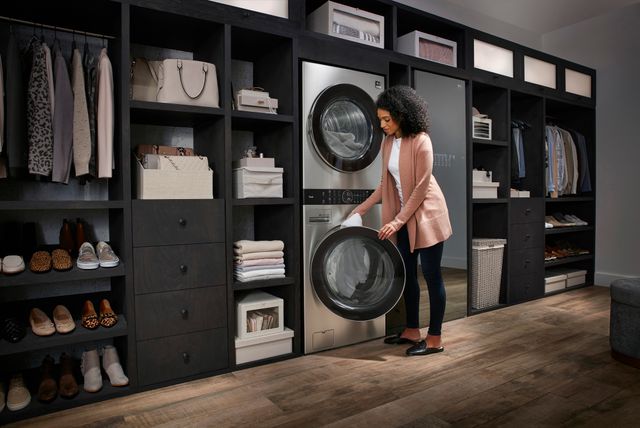 view of a woman loading laundry into a dryer in a luxury laundry room and closer with an LG Styler behind her