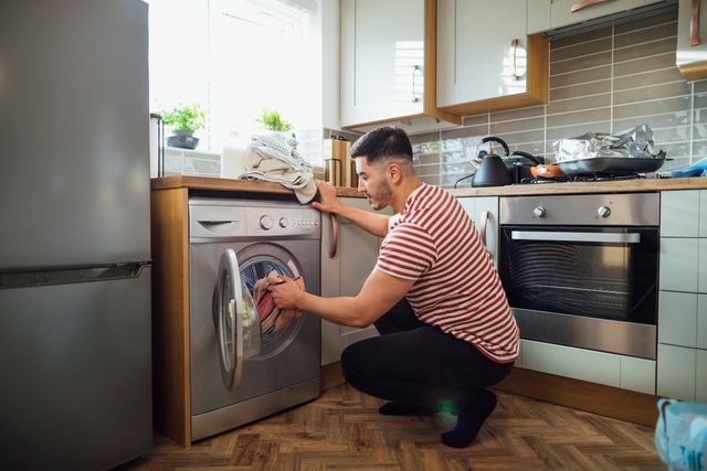 front view of a man loading a front load washing machine