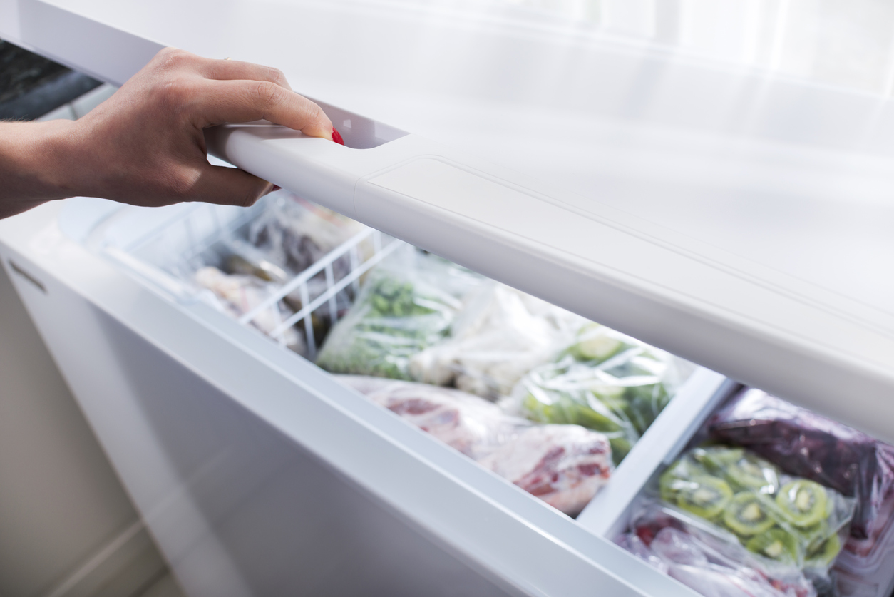 woman reaching into chest freezer