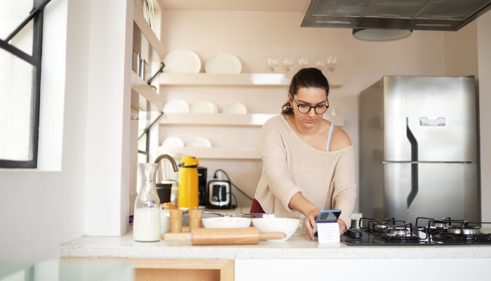 Woman carefully reading recipe and preparing ingredients