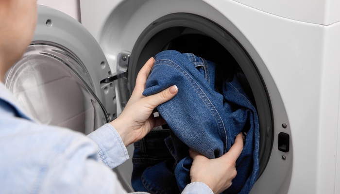 Close up of woman putting jeans in the washer
