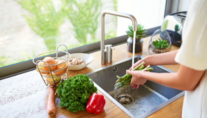 A woman washing produce in preparation for the week