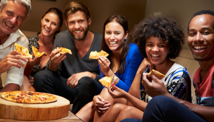 People smiling while eating pizza