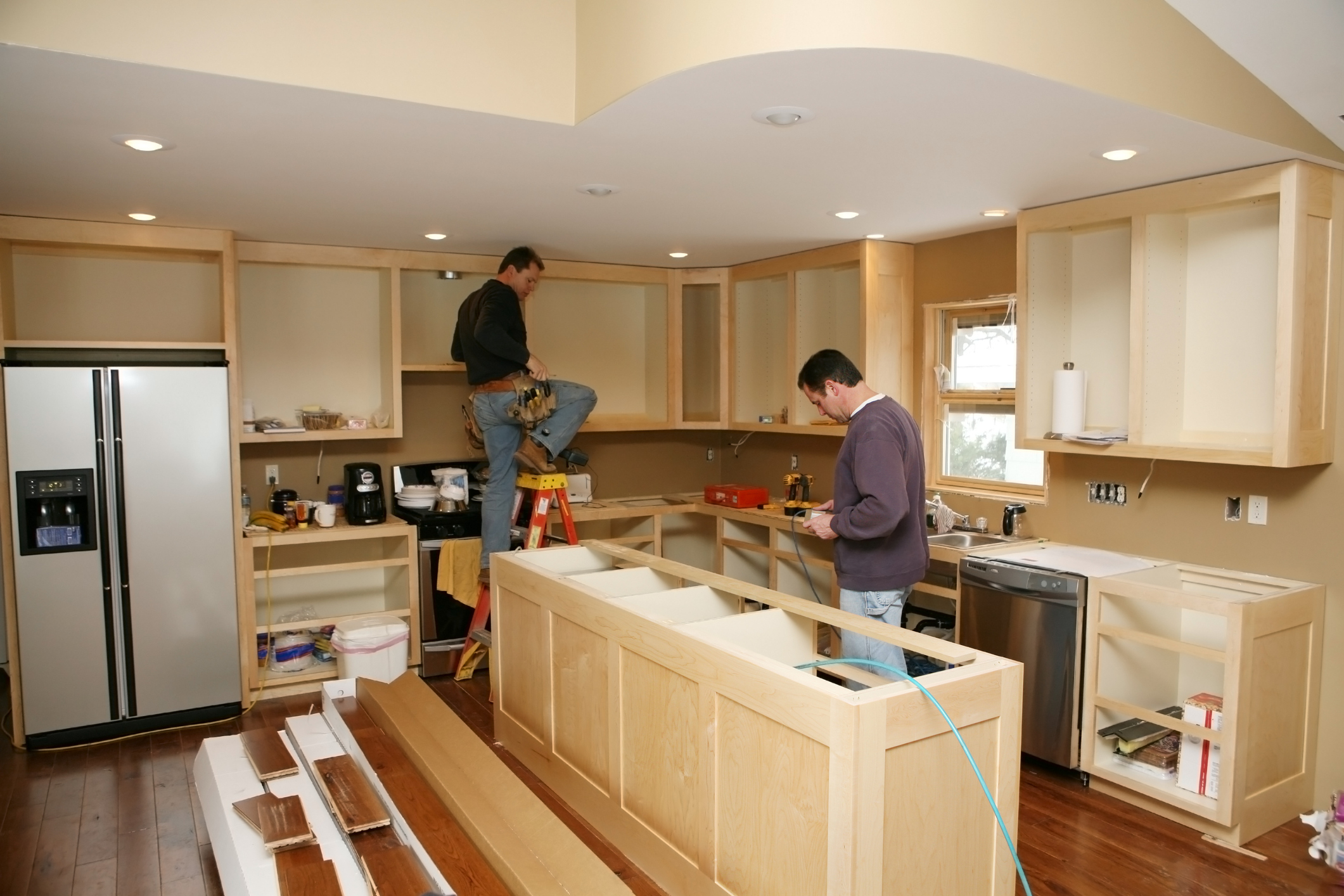 contractors installing cabinetry, countertops, and appliances