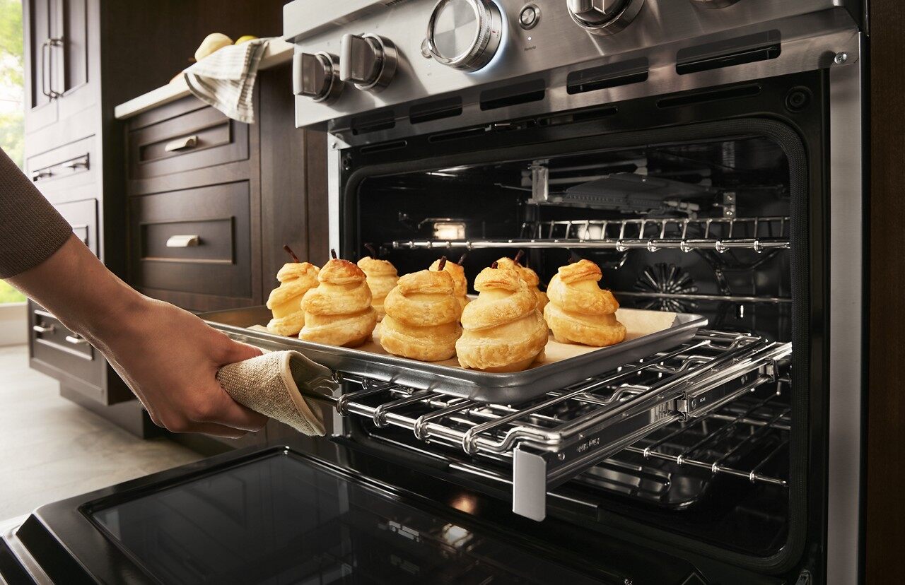 person taking baked goods out of KitchenAid range