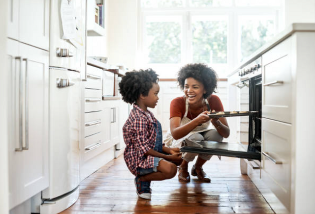 view of a mother and daughter cooking in an all white galley style kitchen