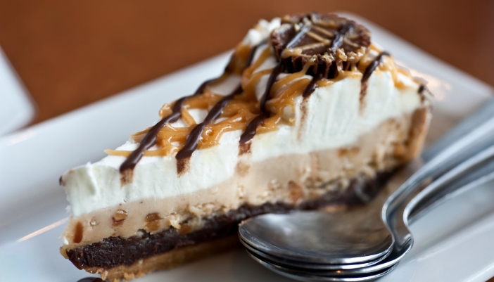A slice of peanut butter pie with a creamy layer on top.