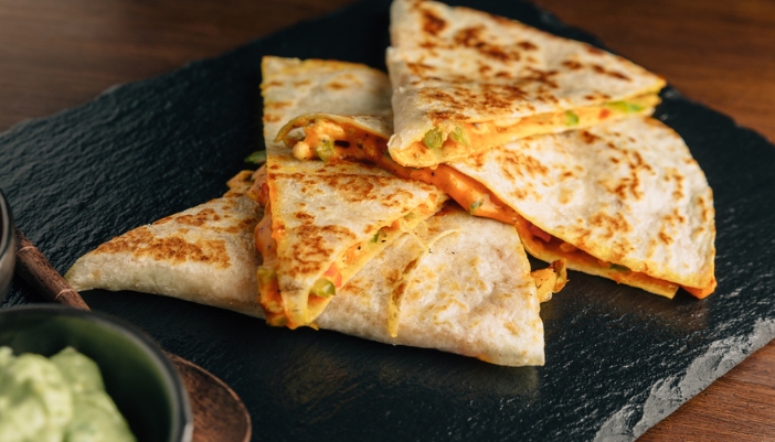 A plate with some quesadilla slices on it.
