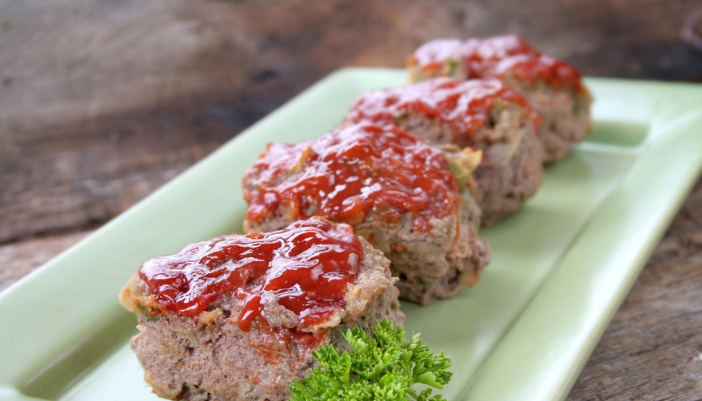 A green plate with mini meatloaf on it.