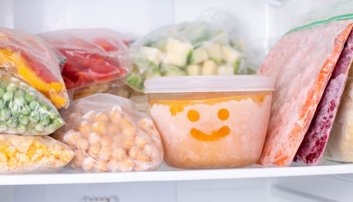 A frozen bowl of soup sits in a freezer with a smiley face in the ice.