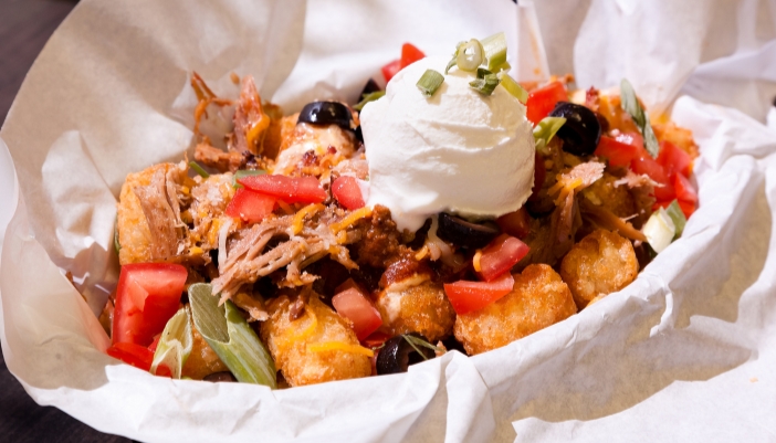 A basket of tater tots with nacho toppings.
