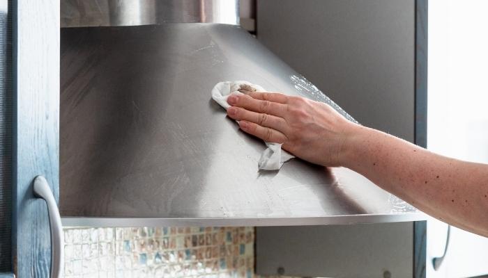 Hand wiping down range hood