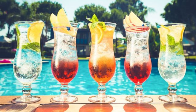 5 fruit daiquiris along the side of a pool 