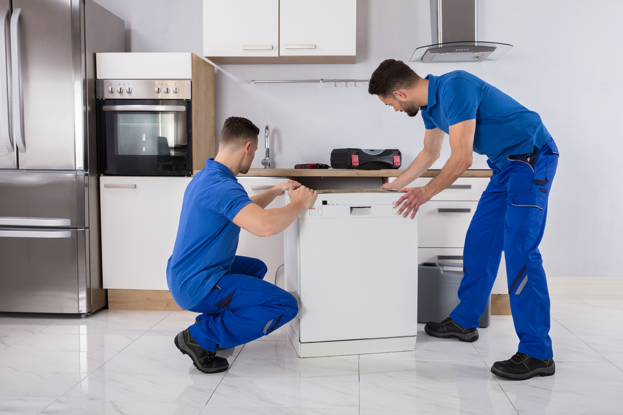 men installing dishwasher into kitchen