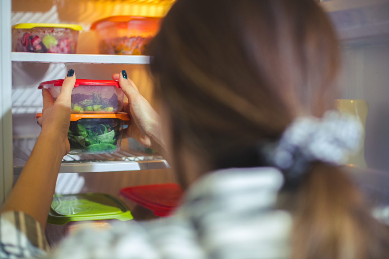 lady putting food into fridge in containers