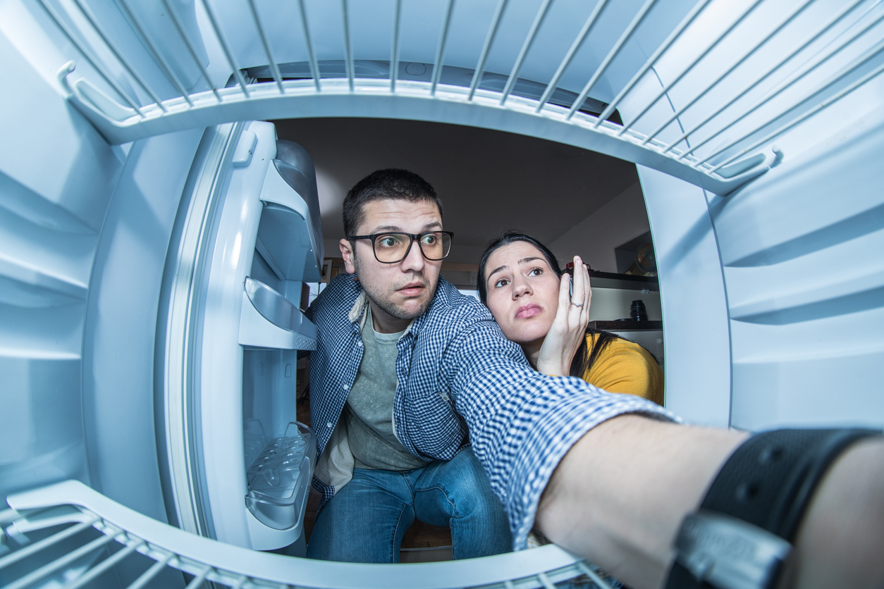 man and woman looking in fridge