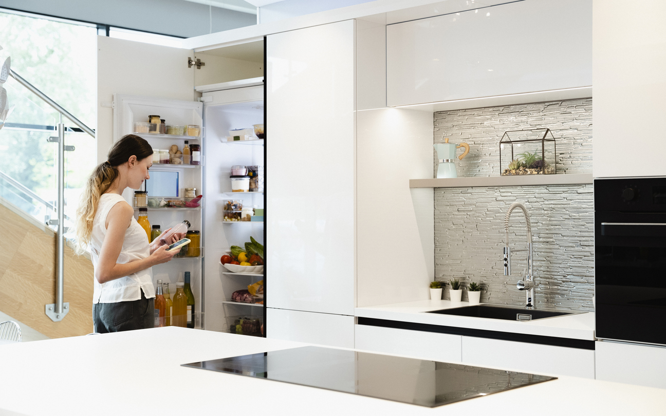 woman with phone in front of modern fridge