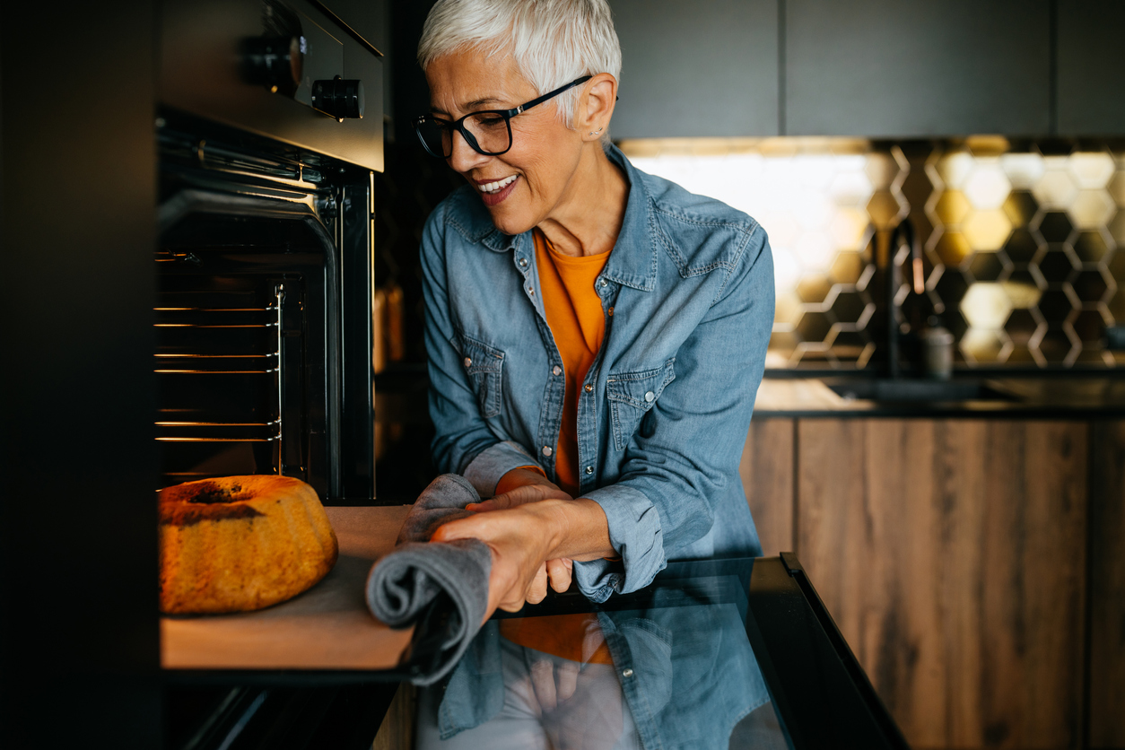 woman pulling baked goods out of oven