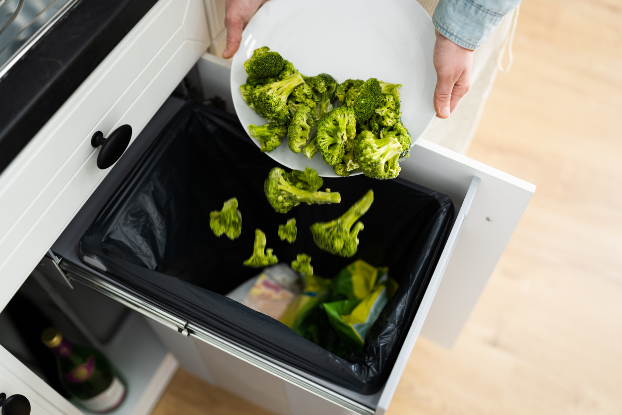 woman throwing food into trash compactor