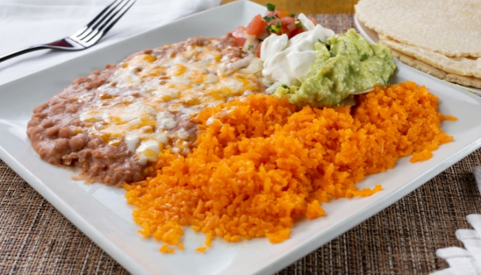 Plate with refried beans, rice, and salsa with tortillas on the side