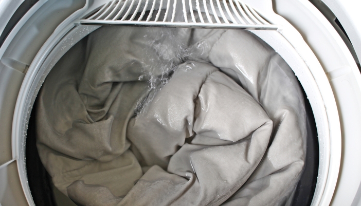 Closeup of a comforter in a washing machine filling up with water